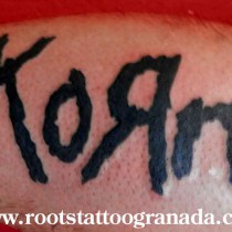 tatuaje logotipo korn, tinta plana, negro, letras, antebrazo, hombre, Serafín Rabé, Roots Tattoo Granada